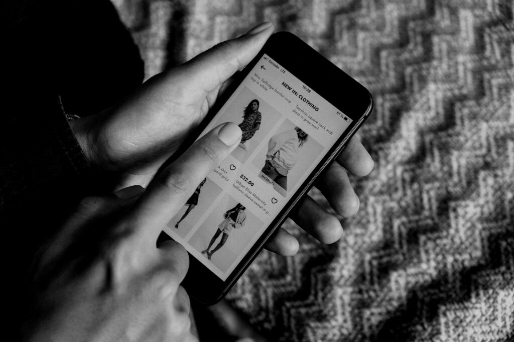 Black and white photo of a pair of hands holding a phone to shop online.