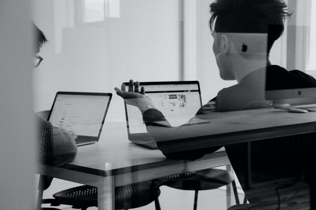 Black and white photo of two digital marketers with laptops open on a table.