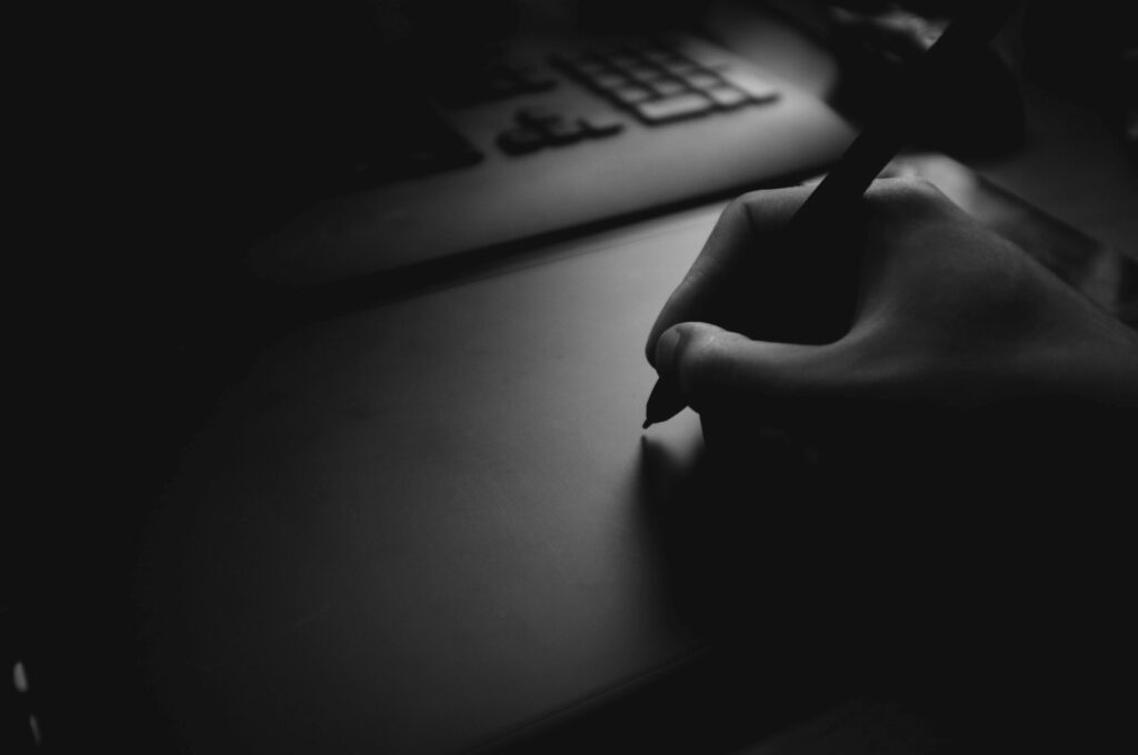 Black and white image of a hand holding a pen to make a web design and development plan